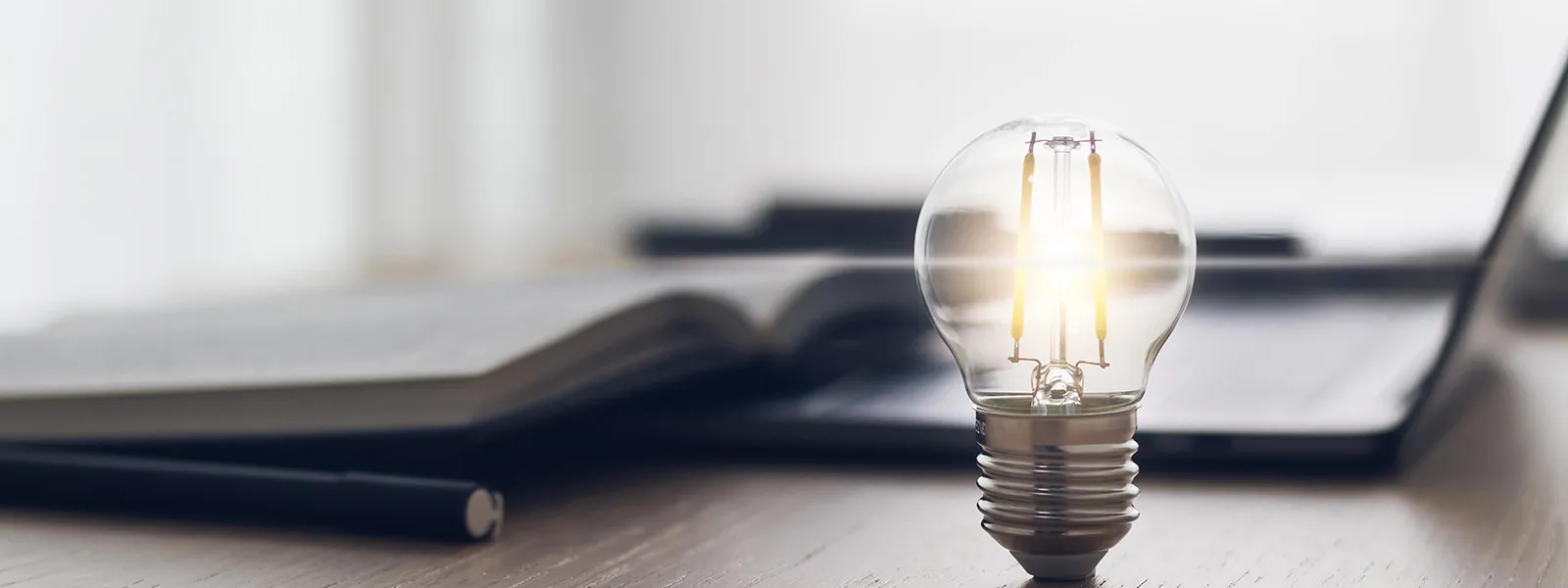 Lightbulb, laptop and notebook on a table